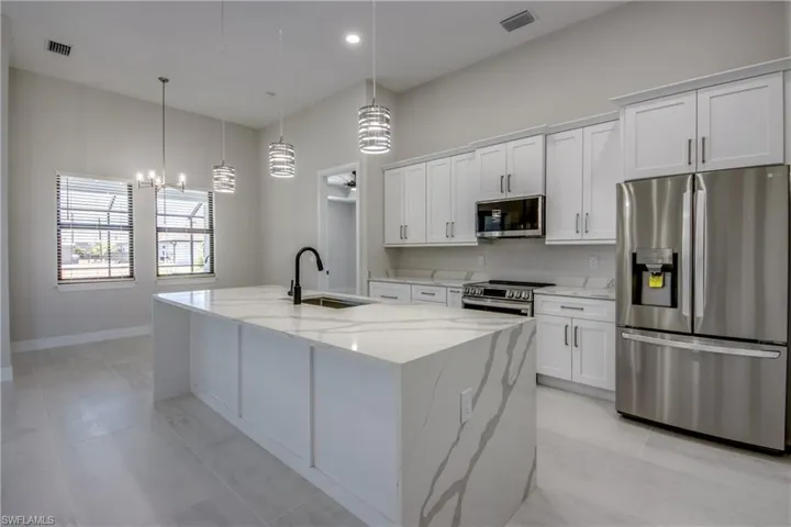 Kitchen featuring visible vents, a sink, an inviting chandelier, stainless steel appliances, and white cabinetry