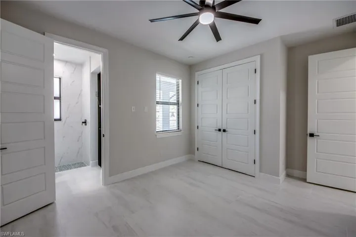 Unfurnished bedroom featuring connected bathroom, a ceiling fan, baseboards, visible vents, and a closet