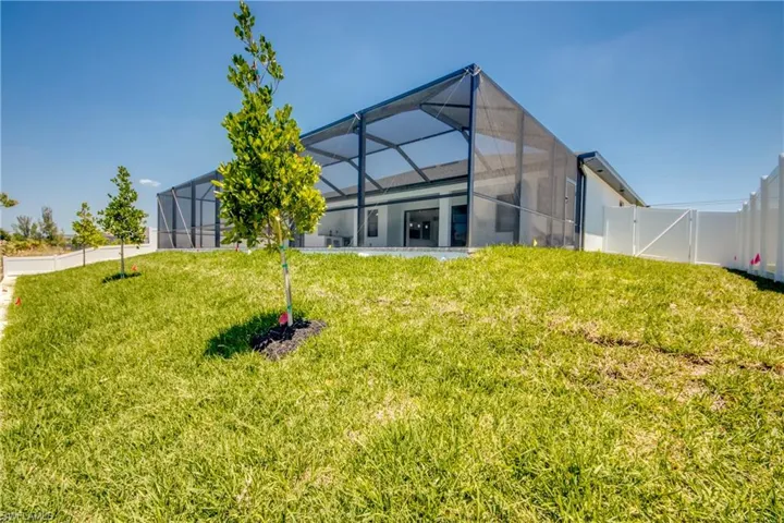 Back of house featuring a lawn, a gate, a fenced backyard, and glass enclosure