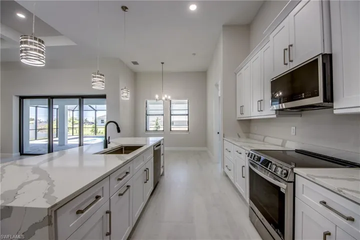 Kitchen featuring an inviting chandelier, recessed lighting, white cabinets, a sink, and stainless steel appliances