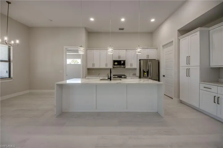 Kitchen with a center island with sink, stainless steel appliances, white cabinetry, and a wealth of natural light