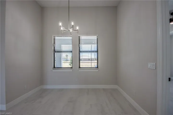 Spare room featuring an inviting chandelier and baseboards