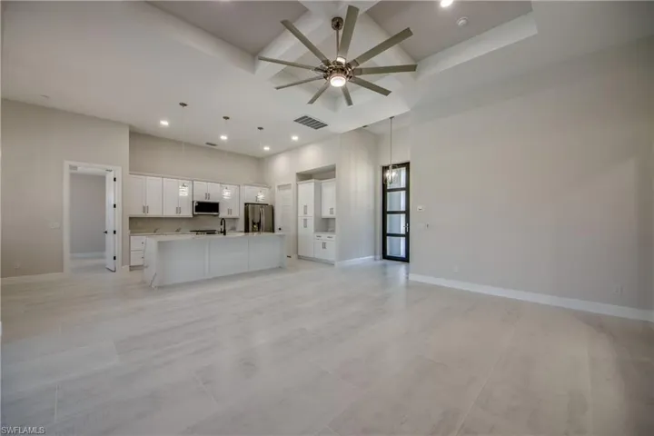 Unfurnished living room featuring visible vents, beam ceiling, baseboards, a ceiling fan, and coffered ceiling