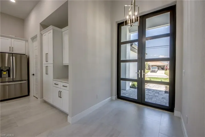 Foyer entrance with light tile patterned floors, baseboards, an inviting chandelier, and french doors