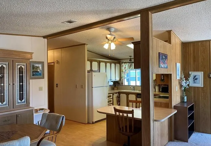Kitchen with lofted ceiling, freestanding refrigerator, a breakfast bar area, a textured ceiling, and a peninsula