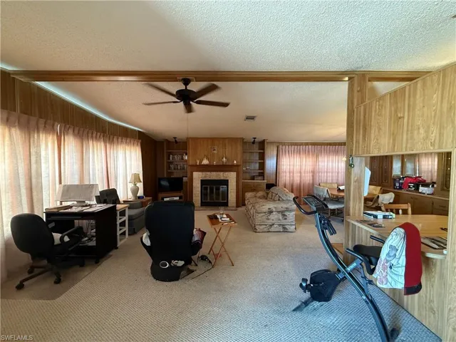 Office featuring a textured ceiling, carpet flooring, a glass covered fireplace, healthy amount of natural light, and built in features