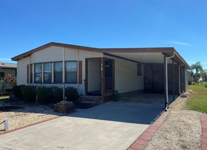 Manufactured / mobile home with concrete driveway, a sunroom, and a carport