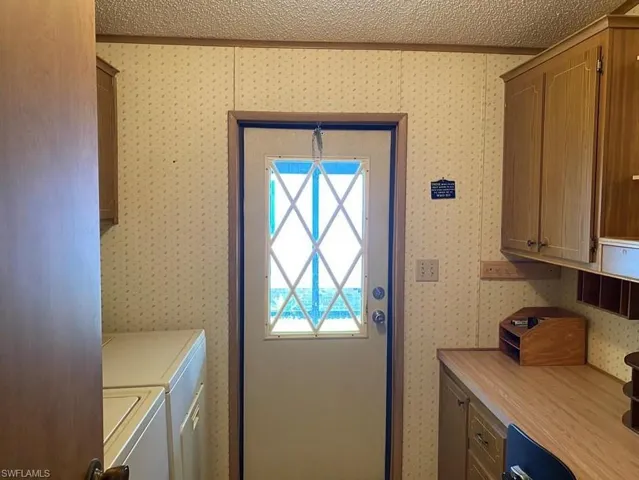 Laundry room with cabinet space, separate washer and dryer, and a textured ceiling
