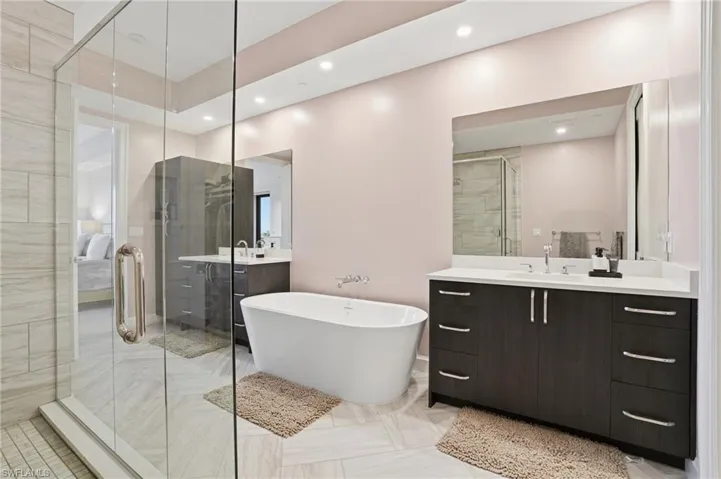 Full bathroom with two vanities, a freestanding bath, recessed lighting, a shower stall, and ensuite bathroom