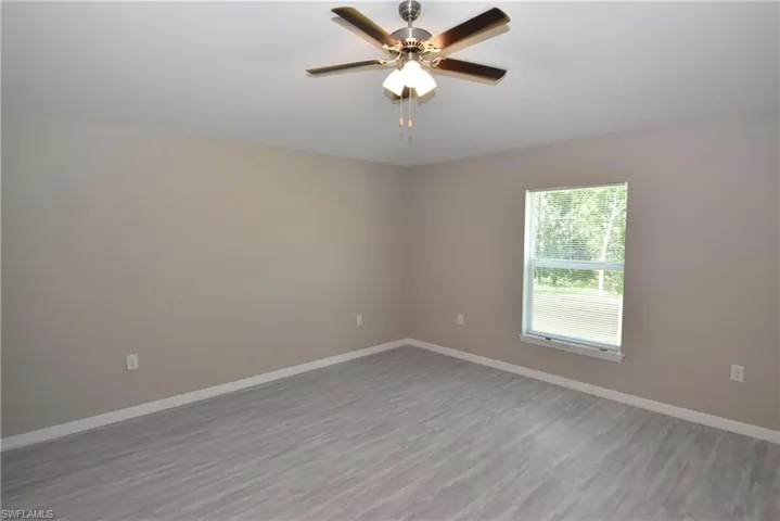 Empty room with wood finished floors and a ceiling fan