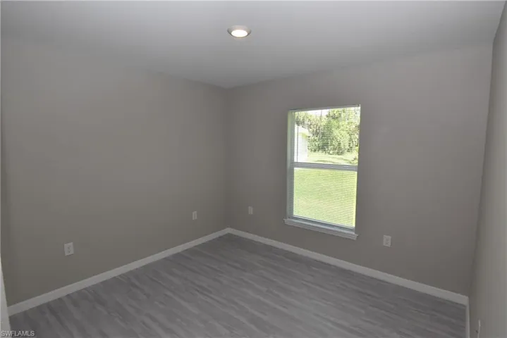 Unfurnished room with baseboards and dark wood-style floors