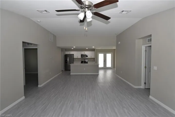 Unfurnished living room featuring french doors, vaulted ceiling, dark wood-type flooring, and a ceiling fan