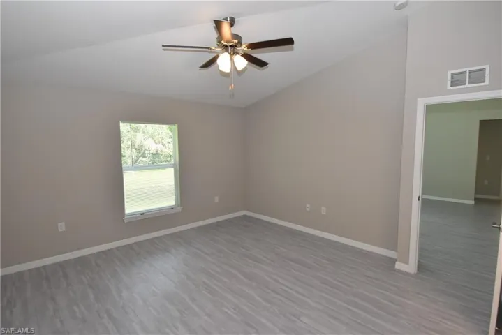Spare room featuring lofted ceiling, light wood-type flooring, and a ceiling fan