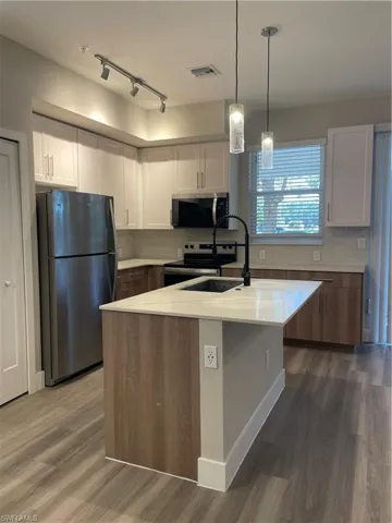 Kitchen with white cabinetry, fridge, rail lighting, electric stove, and hanging light fixtures