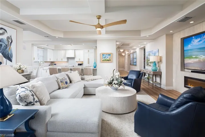 Living room with a ceiling fan, light wood-style floors, coffered ceiling, recessed lighting, and a large fireplace
