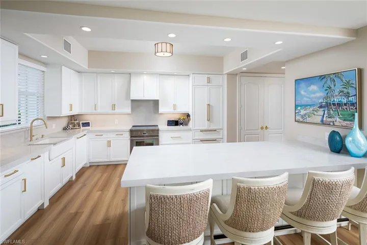 Kitchen featuring stainless steel electric range, a kitchen bar, white cabinets, recessed lighting, and light wood-style floors