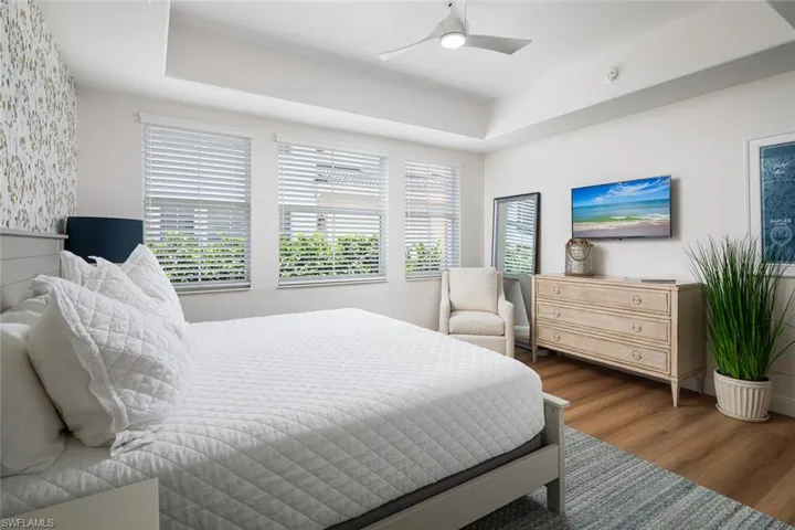 Bedroom with wood finished floors, a raised ceiling, and ceiling fan