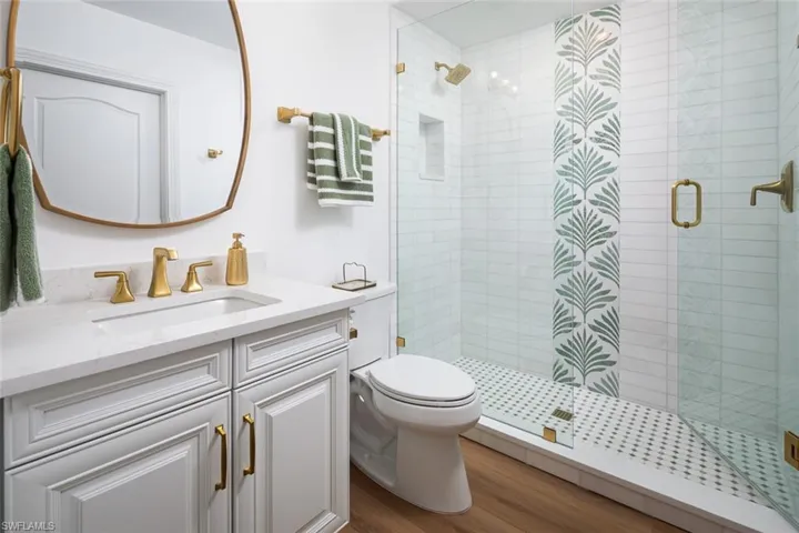 Full bathroom with vanity, a stall shower, and wood finished floors