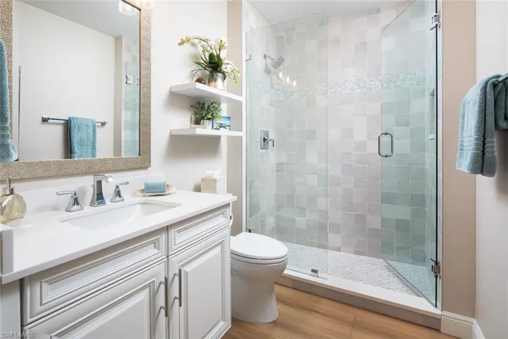Full bath with vanity, a stall shower, and wood finished floors