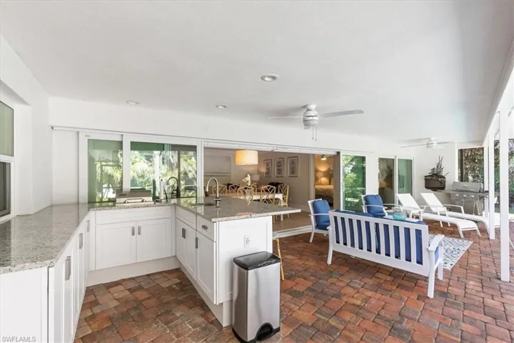 Kitchen featuring light stone counters, white cabinets, a peninsula, and plenty of natural light
