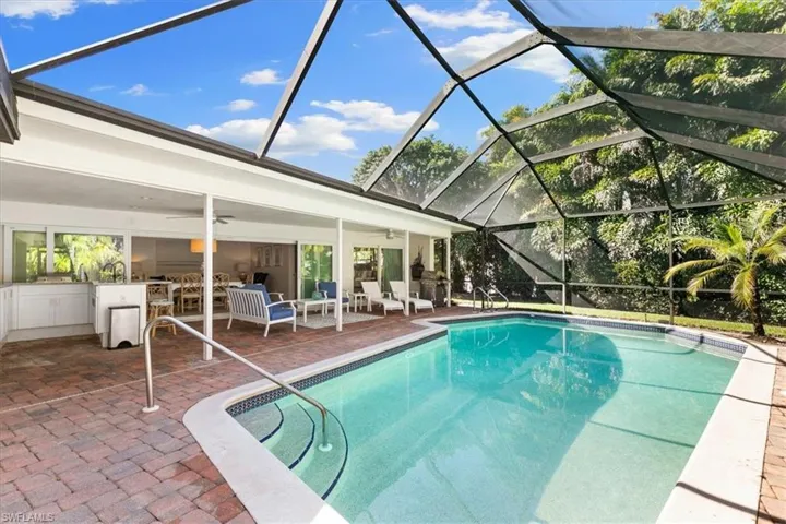 Swimming pool with glass enclosure, a sunroom, and a patio
