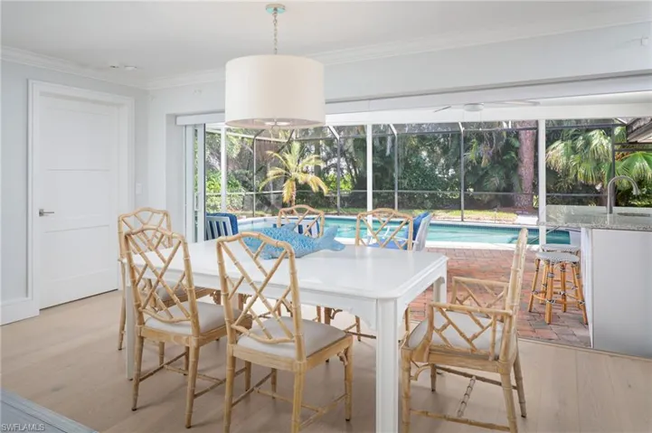 Dining space with a sunroom, ornamental molding, and light wood-type flooring