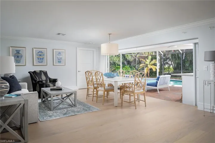 Dining area with ornamental molding, light wood-style flooring, and a sunroom