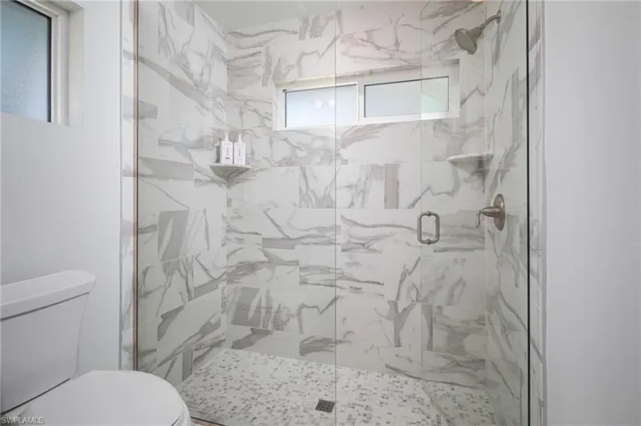 Bathroom with a marble finish shower and toilet