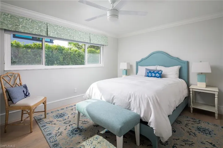 Bedroom featuring a ceiling fan, ornamental molding, and wood finished floors