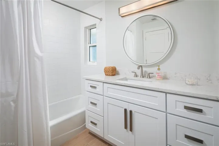 Full bath featuring shower / bathtub combination with curtain, vanity, and light wood-style floors
