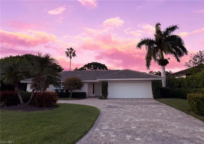 Ranch-style home featuring decorative driveway, a lawn, an attached garage, and stucco siding