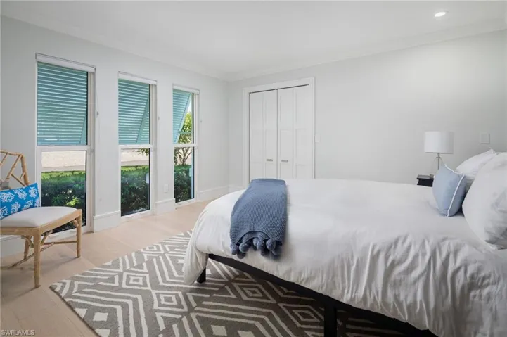 Bedroom with crown molding, light wood-style flooring, and a closet