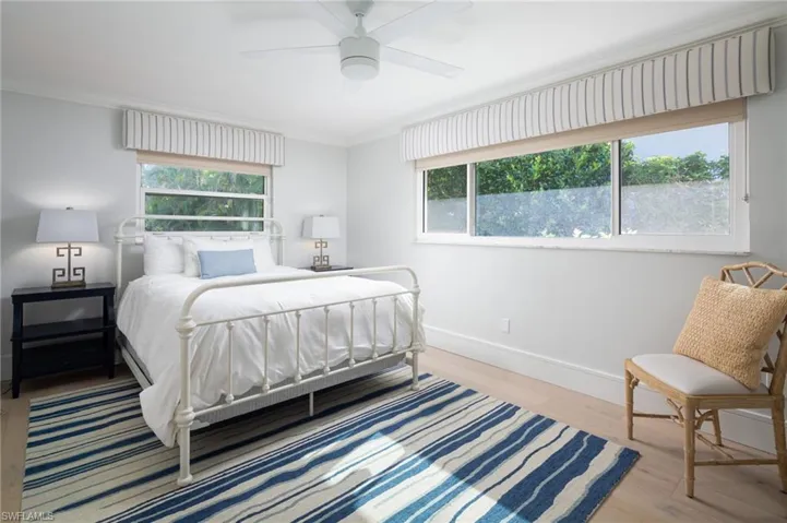 Bedroom with ornamental molding, wood finished floors, and a ceiling fan