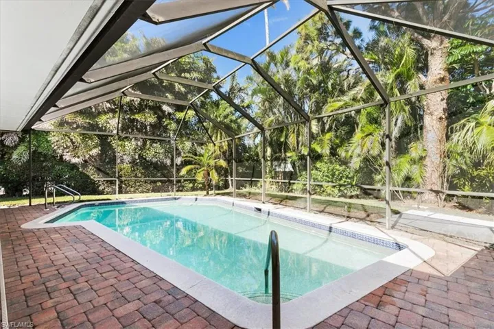 Swimming pool featuring glass enclosure, a sunroom, and a patio