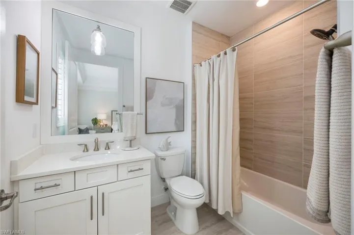 Full bathroom with vanity, shower / bath combination with curtain, and light wood finished floors