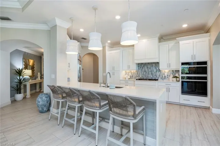 Kitchen with a breakfast bar, arched walkways, white cabinets, tasteful backsplash, and a peninsula