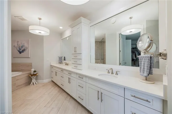 Full bath featuring double vanity, a walk in closet, a garden tub, and a stall shower