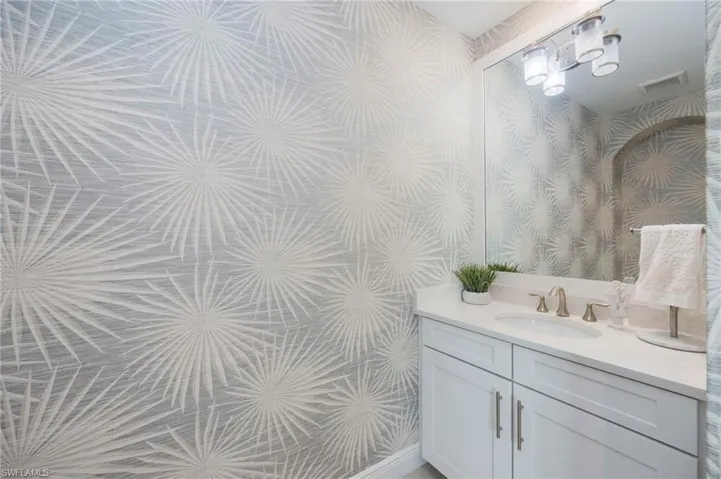 Bathroom with wallpapered walls and vanity