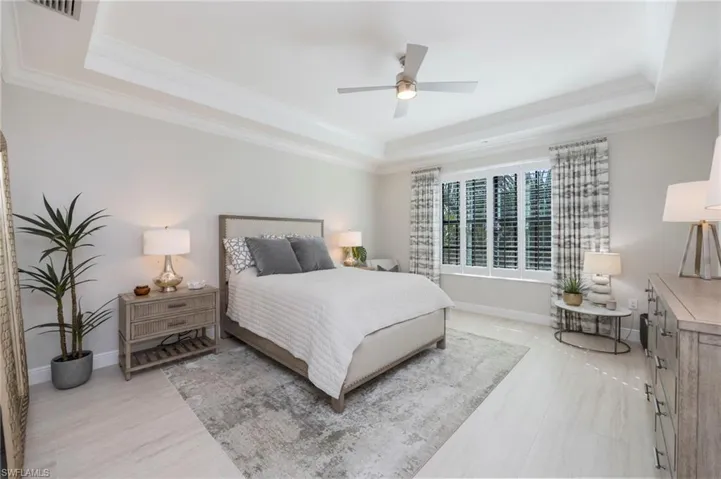 Bedroom with a ceiling fan, crown molding, and a tray ceiling