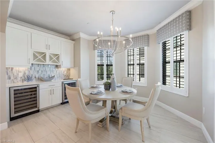 Dining room with beverage cooler, ornamental molding, suspended lighting, and a dry bar