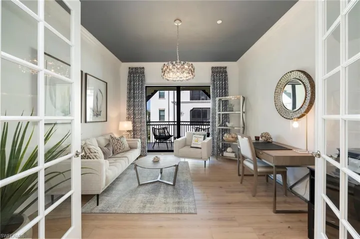 Living area with crown molding, light wood-style floors, a chandelier, and french doors