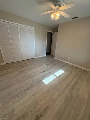 Unfurnished bedroom with light wood-style flooring, ceiling fan, and a closet