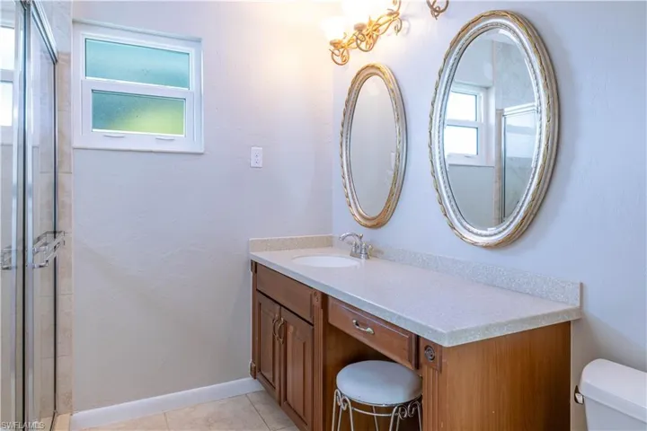 Bathroom with tile patterned flooring, toilet, vanity, and a shower with shower door