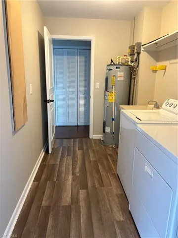 Laundry room featuring dark wood-type flooring, water heater, and independent washer and dryer