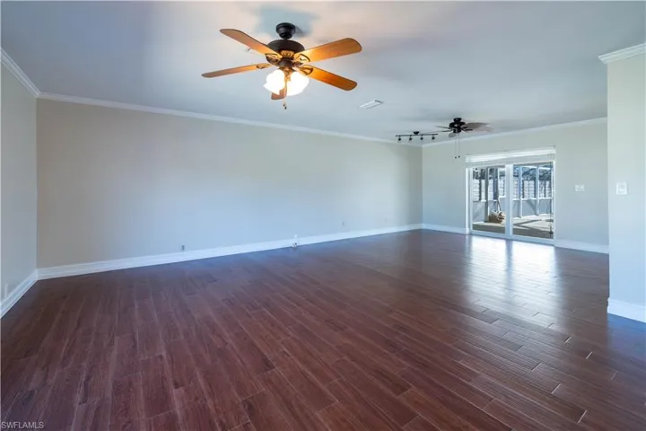 Spare room with dark wood-style floors, ceiling fan, baseboards, and ornamental molding