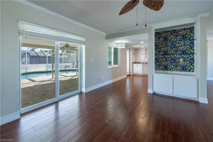 Spare room with baseboards, dark wood-style flooring, a sink, ceiling fan, and crown molding