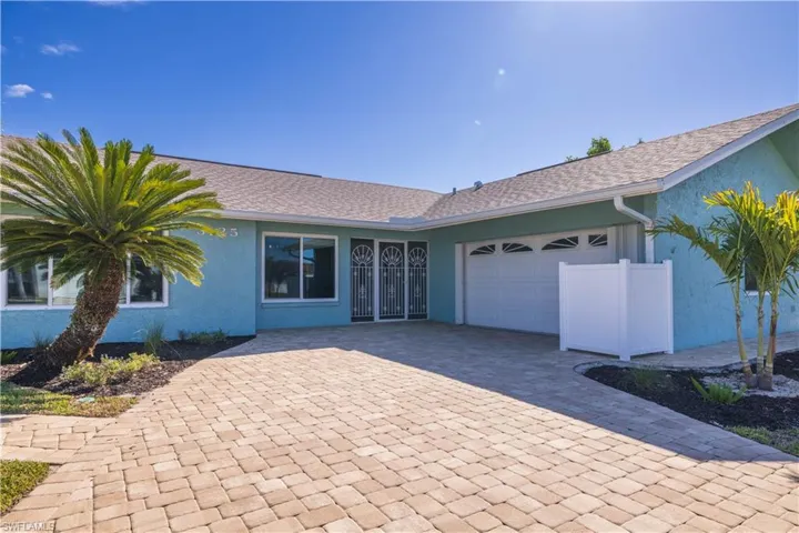 Single story home featuring an attached garage, roof with shingles, stucco siding, and decorative driveway