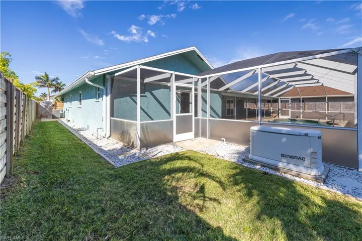 Rear view of house with a lawn, a fenced backyard, stucco siding, a swimming pool, and a lanai