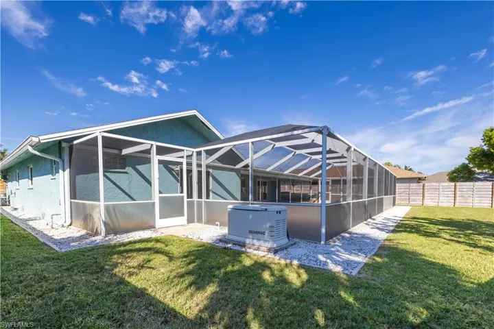 Rear view of property with glass enclosure, fence, a lawn, and stucco siding