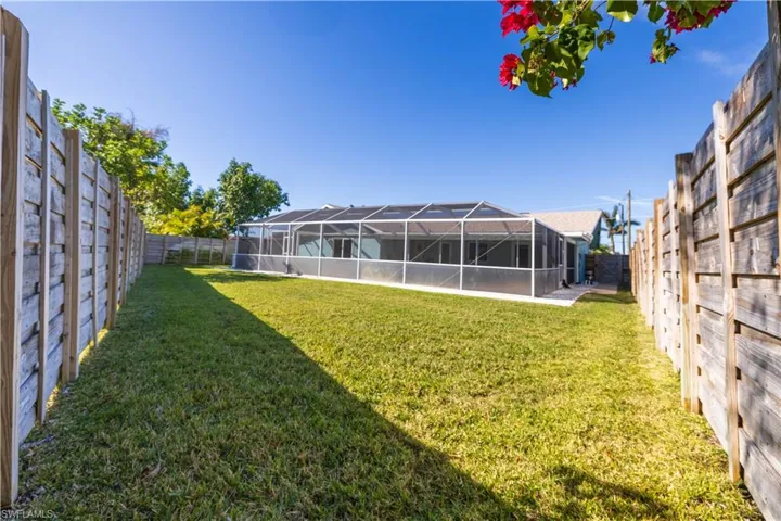 View of yard featuring a fenced backyard and glass enclosure